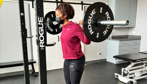 Woman lifting weight while using a BFR tool on her leg